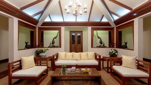 A spacious living area with a high ceiling, wooden furniture, and a central sofa.