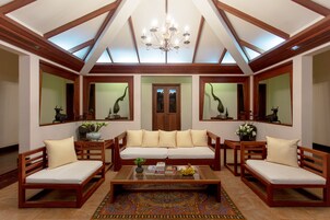 Un amplio salón con techo alto, muebles de madera y un sofá central.
