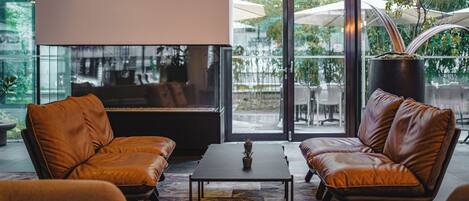 A modern lounge area with leather sofas, a central table, and a piano.