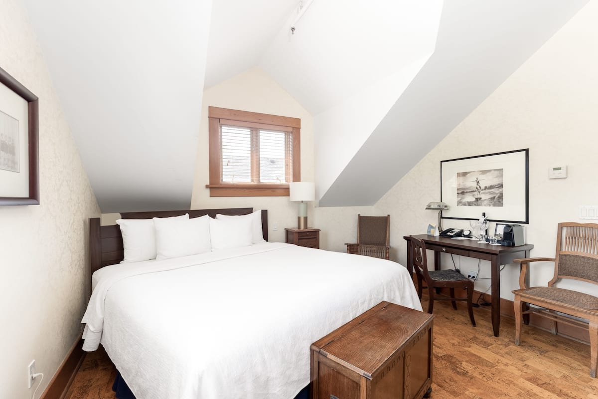 Ein Schlafzimmer mit einem großen Bett, einem Schreibtisch, einem Stuhl und einem Fenster.