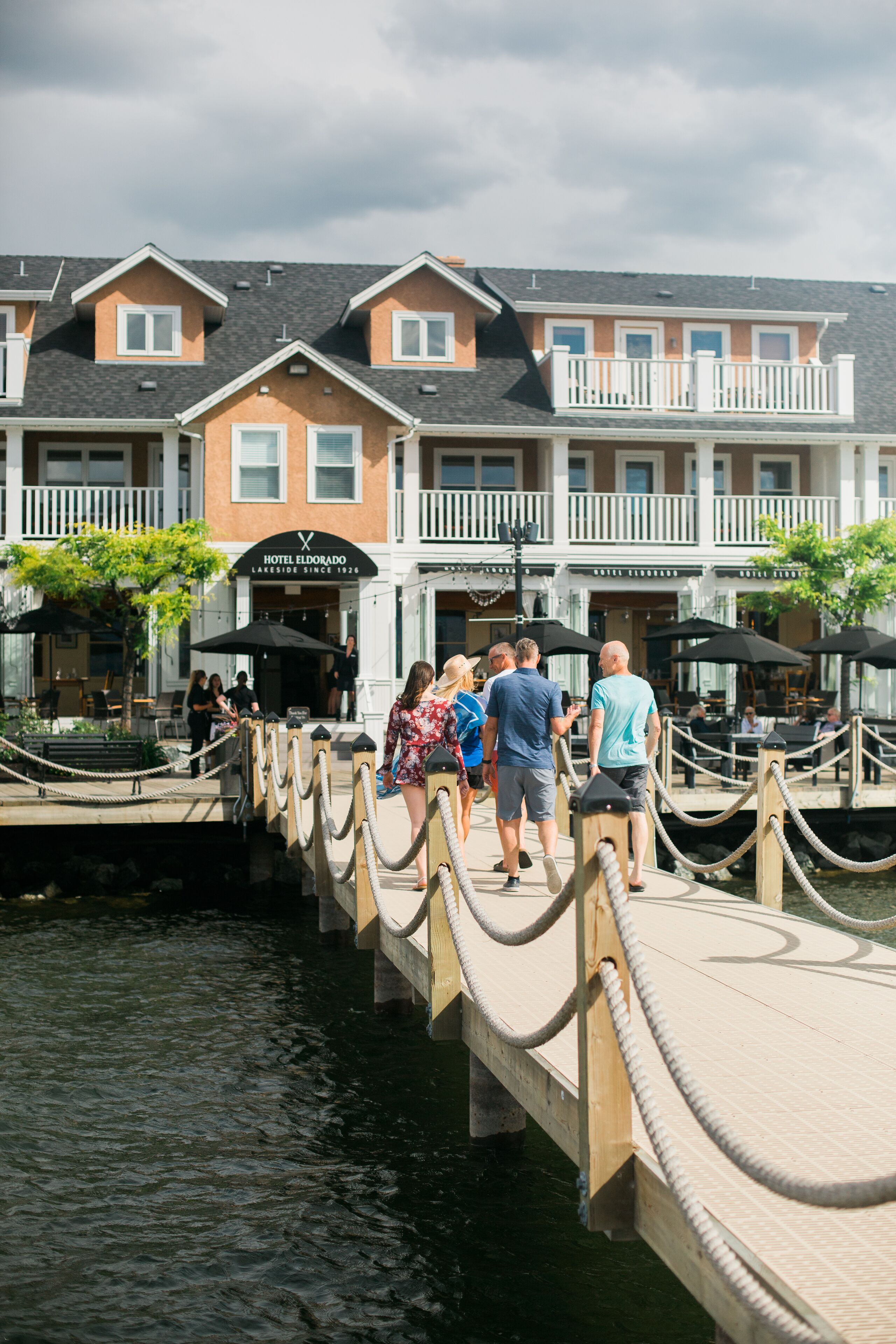 A wooden dock leading to a hotel with a sign reading "Hotel Eldorado Lakeside Since 1926".