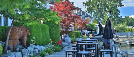 A wooden deck with outdoor seating, a bear sculpture, and a red-leaved tree.
