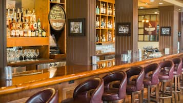 A bar area with multiple liquor bottles, glasses, and a wooden bar counter.