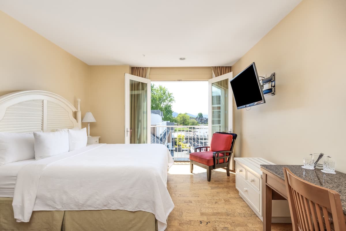 Ein Hotelzimmer mit Bett, Schreibtisch, Stuhl, Fernseher und einem Balkon mit Blick.