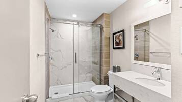 A modern bathroom with a glass-enclosed shower, a white toilet, and a marble-tiled floor.