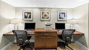 A workspace with two desks, two chairs, and three framed pictures on the wall.