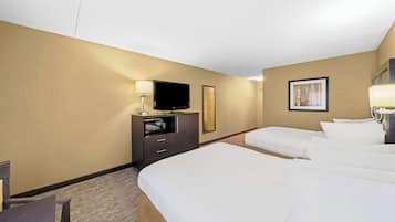 A hotel room with a large bed, a TV on a dresser, a desk, and a painting on the wall.
