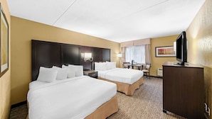 A hotel room with two beds, a desk, a television, and a wardrobe.