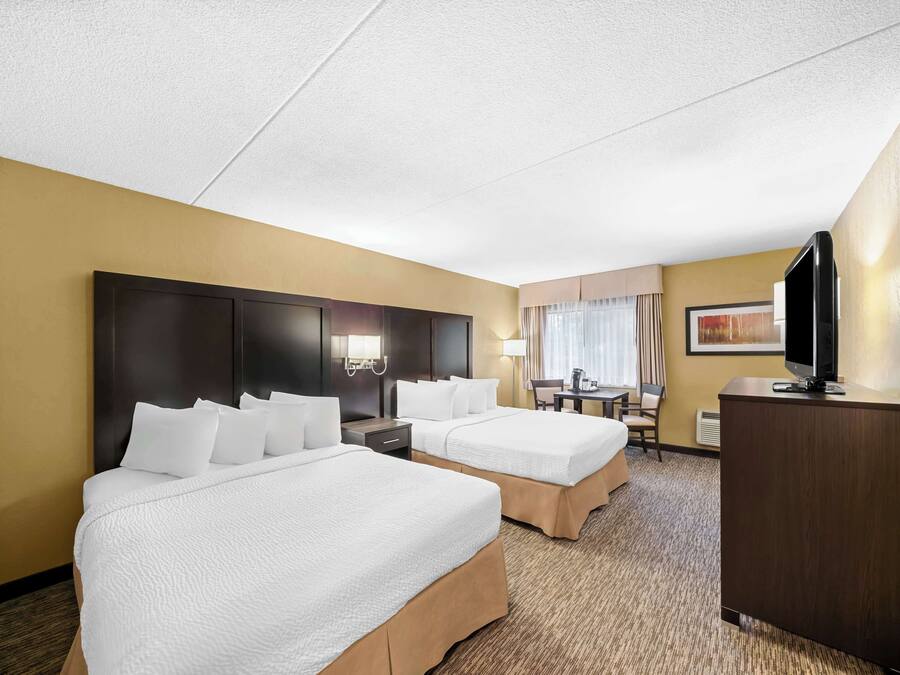 Een hotelkamer met twee bedden, een bureau, een televisietoestel en een kledingkast.