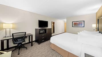 Une chambre d’hôtel avec un lit, un bureau, une chaise, une télévision et un tableau encadré au mur.
