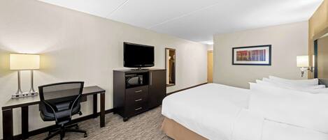 A hotel room with a bed, desk, chair, television, and a framed picture on the wall.