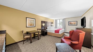Une chambre d’hôtel comprenant un lit, un bureau, une chaise, une télévision et une commode.