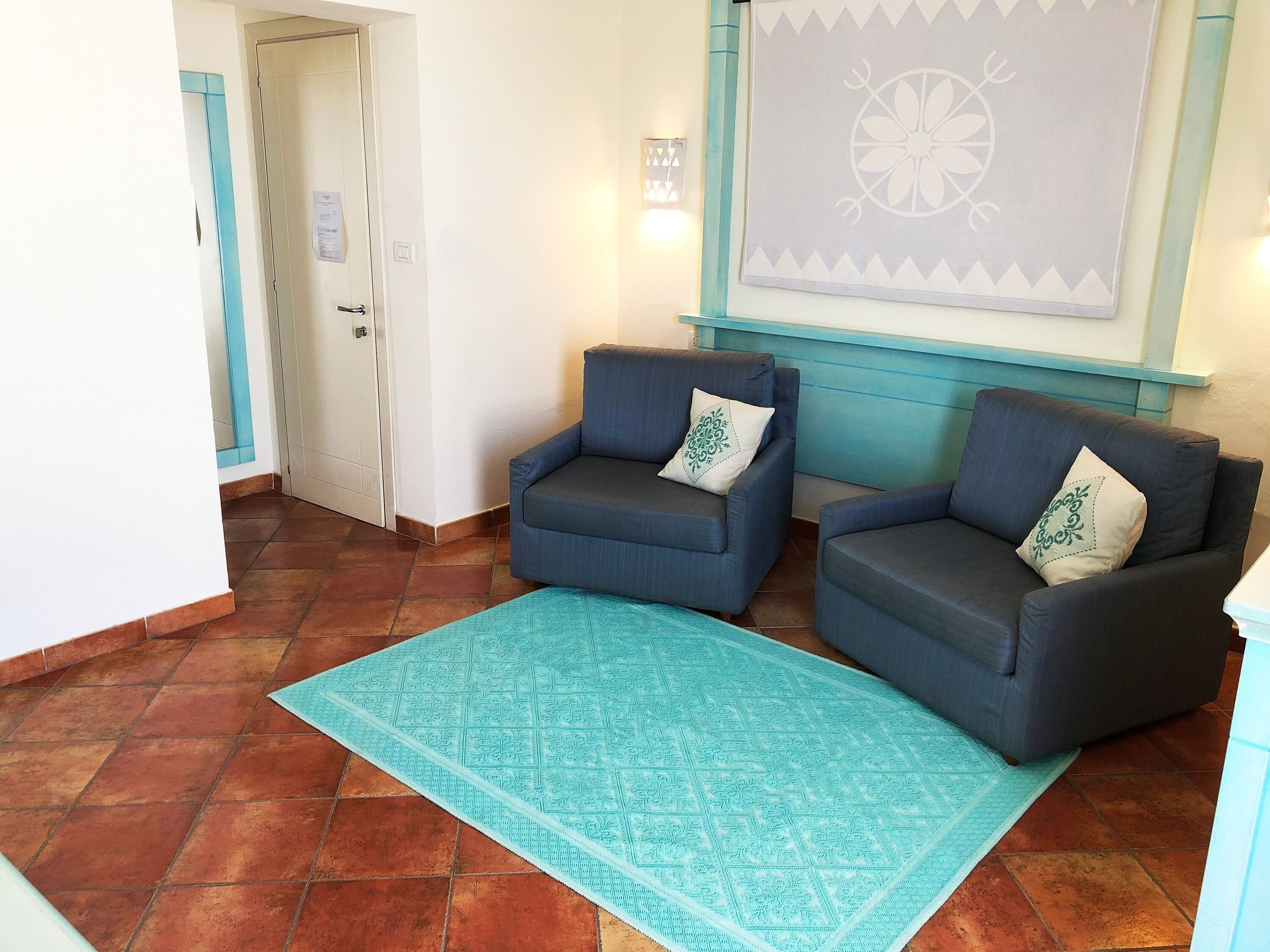 A room with two armchairs, a patterned rug, and a wall with a decorative piece.