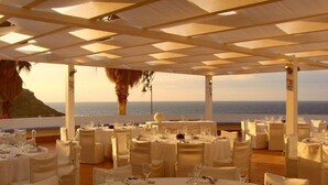 An outdoor dining area with round tables set for a meal, overlooking the sea. - LH Pedraladda Resort (Castelsardo)