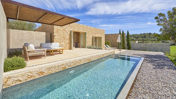 Un espace piscine extérieur moderne, agrémenté de murs en pierre, de chaises longues et d’une pergola.