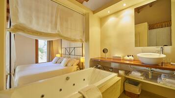 Habitación de hotel con una cama grande, baño independiente con bañera y tocador con lavamanos y espejo.
