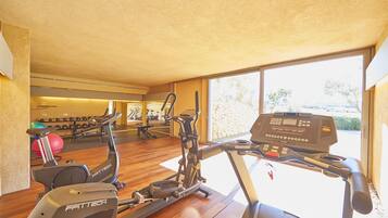 A gym with exercise equipment, a wooden floor, and a large window.