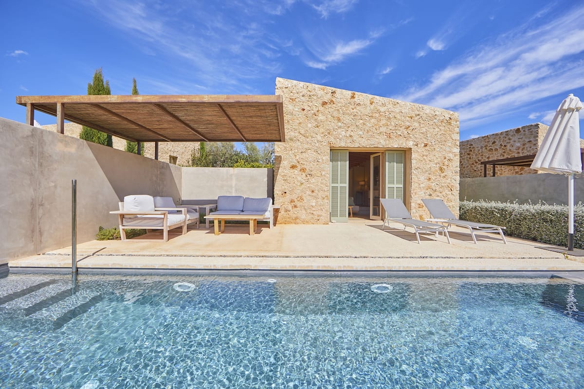Un espace piscine extérieur moderne, doté de chaises longues et d’un coin salon abrité.