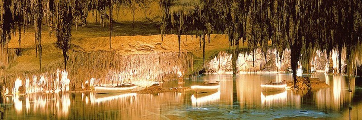 Eine Höhle mit Stalaktiten und Stalagmiten, einem stillen See und Booten.