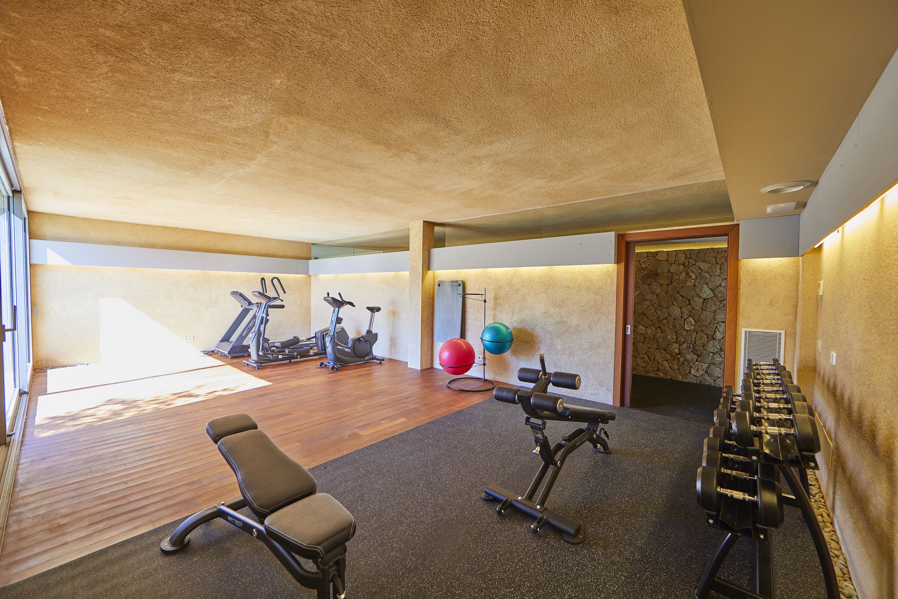 Een sportschool met trainingsapparatuur, een loopband en een hometrainer.