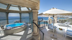 A rooftop terrace with a hot tub, lounge chairs, and a view of the sea. - Queen of Sheba Eilat Hotel (Eilat)