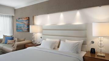 Una habitación de hotel con una cama grande, dos mesitas de noche, una lámpara de pared y un cuadro.