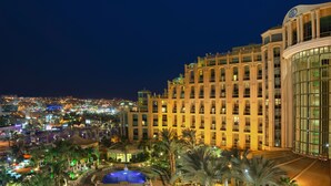 A hotel with multiple swimming pools, palm trees, and a cityscape view in the background. - Queen of Sheba Eilat Hotel (Eilat)