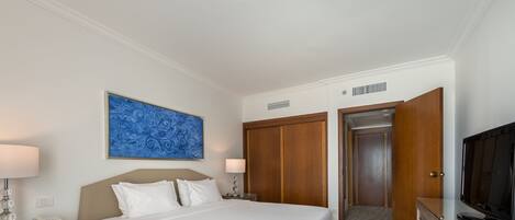 Una habitación de hotel con una cama grande, un escritorio con lámpara, televisión y armario.