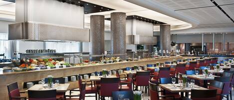 A spacious restaurant with high ceilings, a central bar area, and multiple dining tables and chairs.