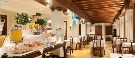 A restaurant with a checkered floor, wooden beams, and tables set for dining.