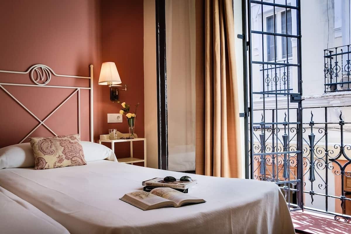 Une chambre d’hôtel avec un lit, une table de chevet, une lampe et une vue sur le balcon extérieur.