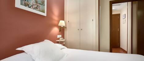A hotel room with a bed, a nightstand, a lamp, a painting, and a wardrobe.