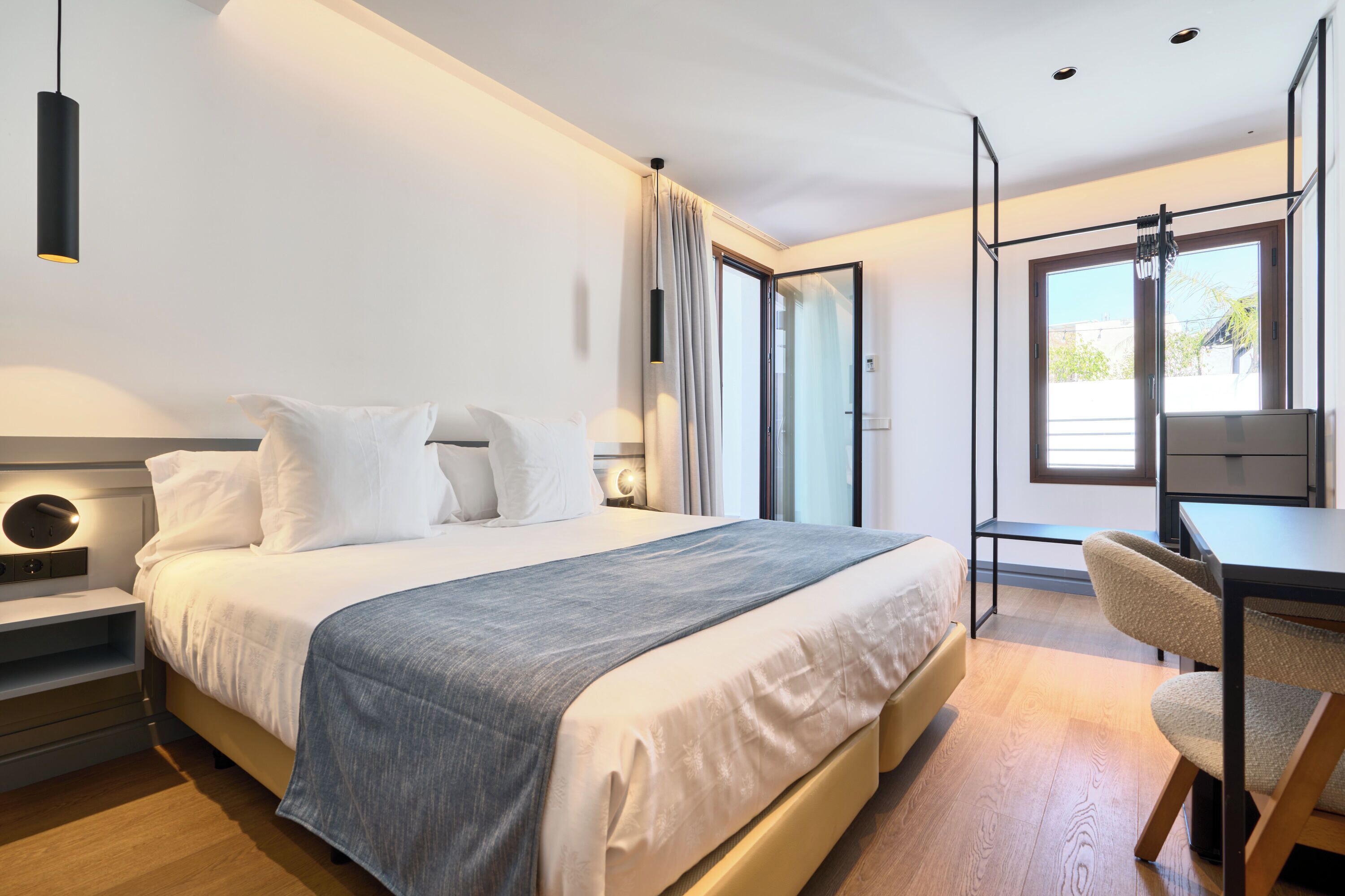 A modern hotel room with a large bed, a desk, and a chair.