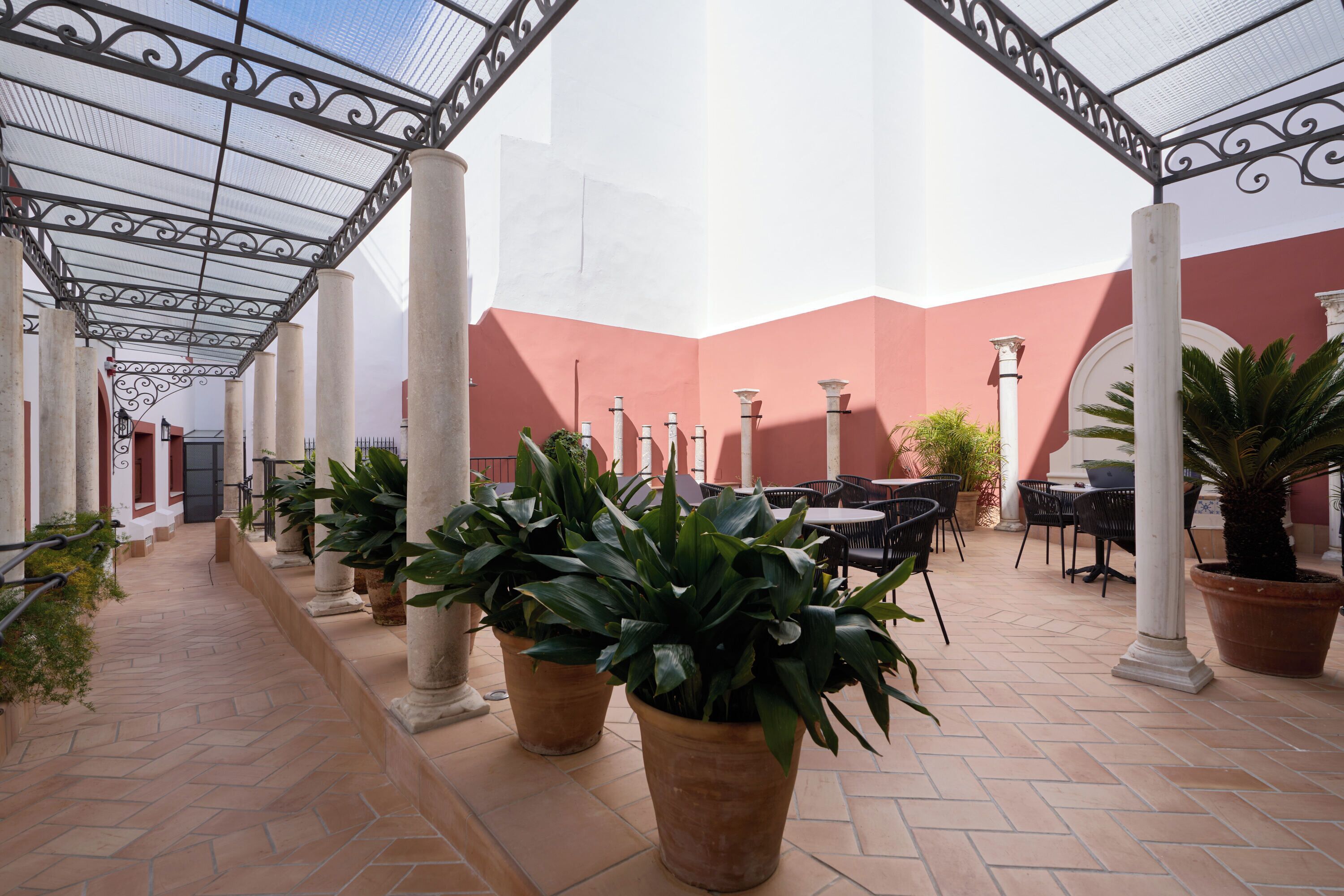 Un espacio exterior cubierto con piso de baldosas, plantas en macetas y asientos al aire libre.