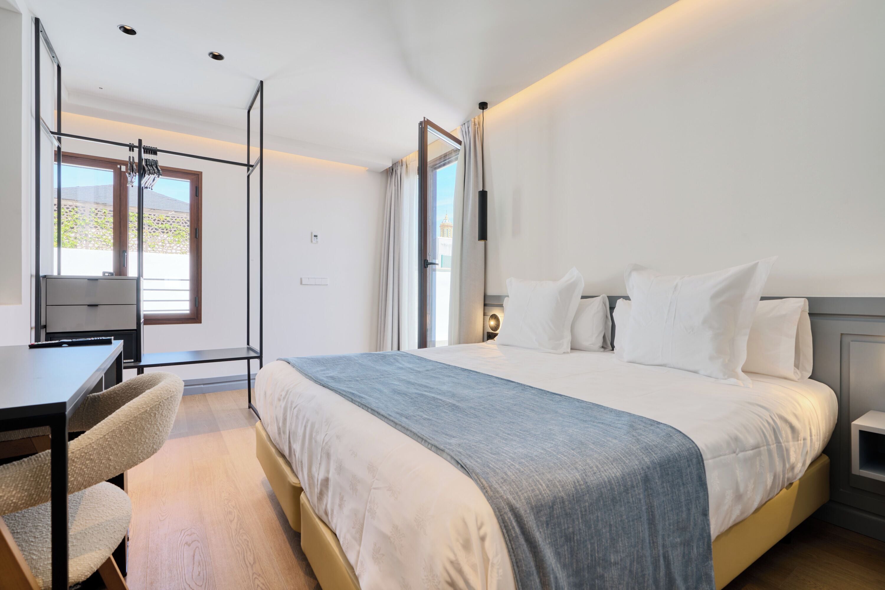 A modern bedroom with a large bed, a desk, and a chair.