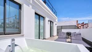 Un baño exterior moderno con bañera, ventana y una silla.