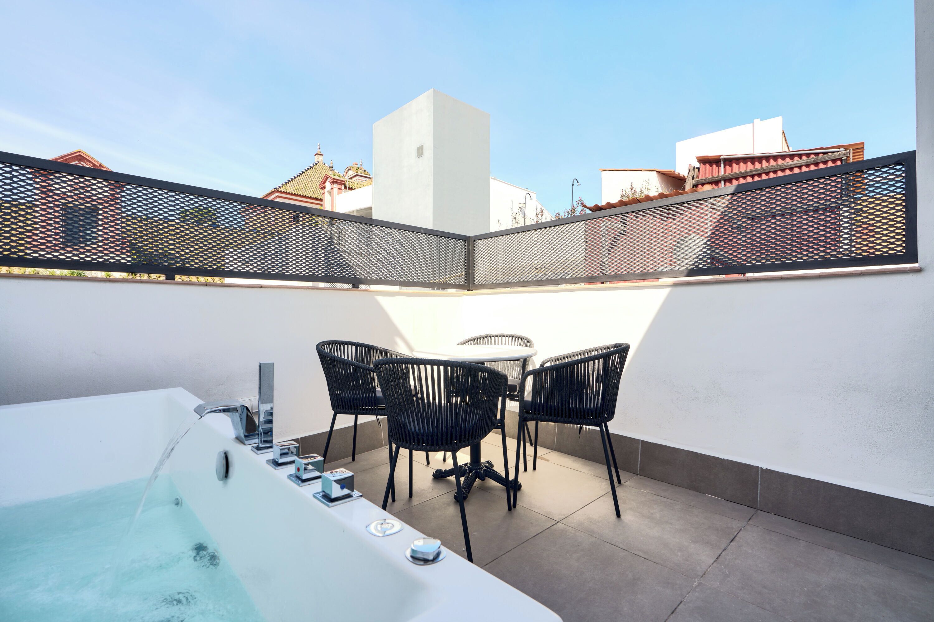 Una terraza en la azotea con hidromasaje, sillas negras y una mesa.