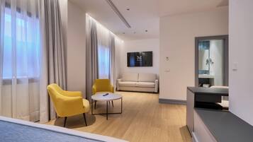 Una habitación de hotel moderna con una cama, un sillón amarillo, una pequeña mesa redonda, un sofá y un televisor montado en la pared.