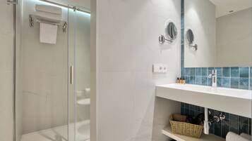 Un baño moderno con ducha envuelta en vidrio, un lavabo blanco con espejo y un salpicadero de azulejos.