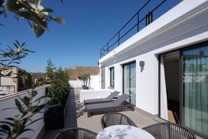 A rooftop terrace with two lounge chairs, a table, and potted plants. - Hotel Murillo Reinoso (Seville)