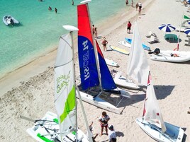 Una spiaggia con diverse barche a vela e persone.