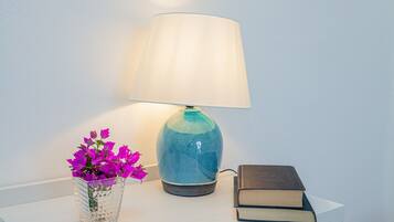 Un tavolo con una lampada, un vaso di fiori e un libro.