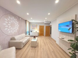 Una sala de estar moderna con un sofá beige, una mesa de centro y un televisor montado en la pared.