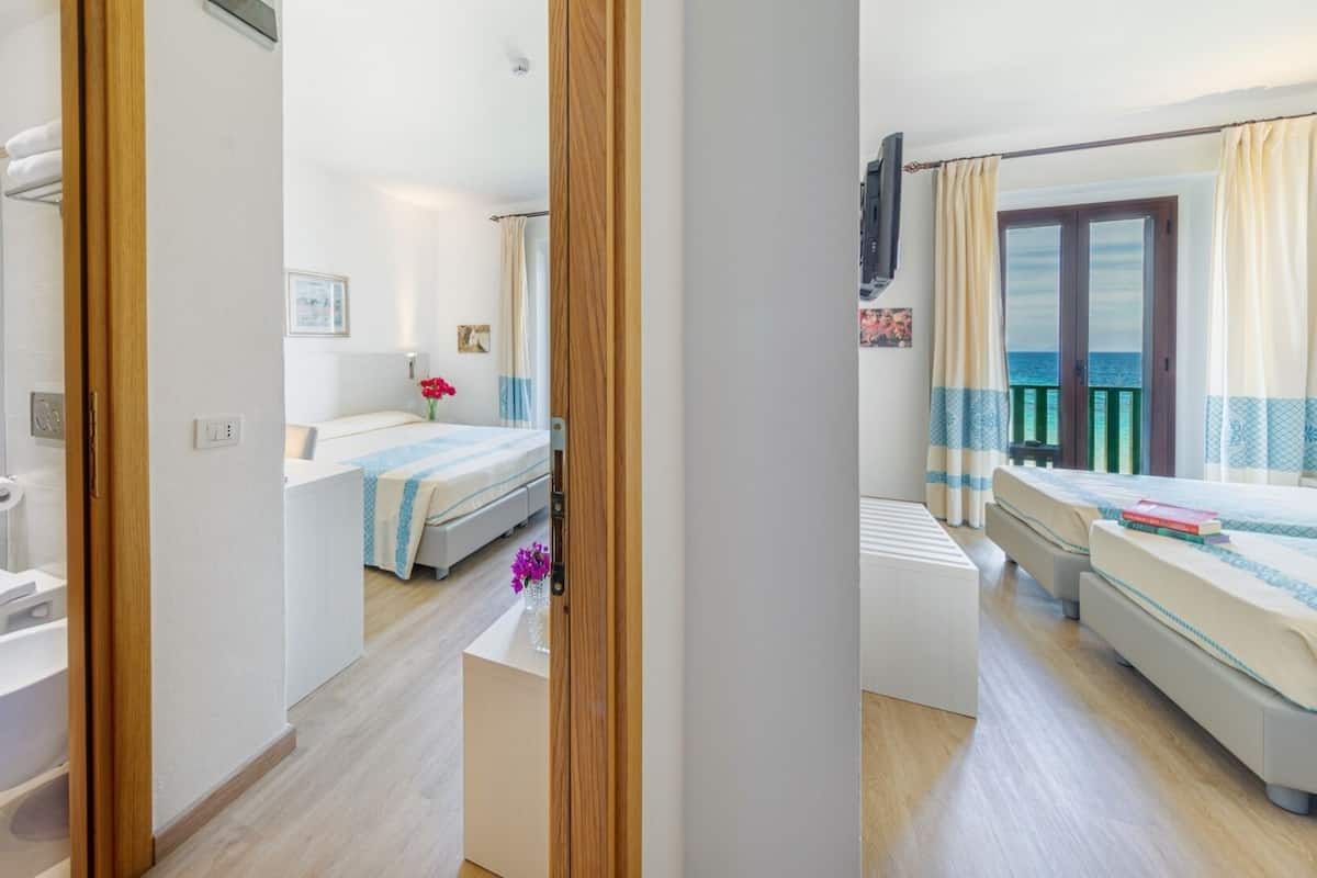 Ein modernes Hotelzimmer mit Dusche, WC, Bett und einem Balkon mit Blick.