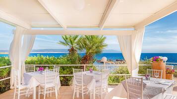 Un patio al aire libre con mobiliario blanco y vista al mar.