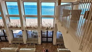 A spacious indoor area with multiple seating arrangements and a view of the sea through large windows. - Hotel dei Pini (Alghero)