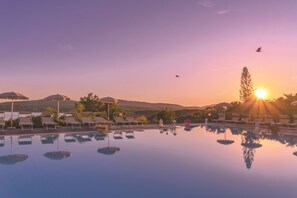 Una piscina al aire libre, sombrillas, sillones reclinables de piscina