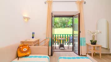 Relax in this serene hotel room with a garden view, featuring two beds, a desk, and a balcony with outdoor seating.
