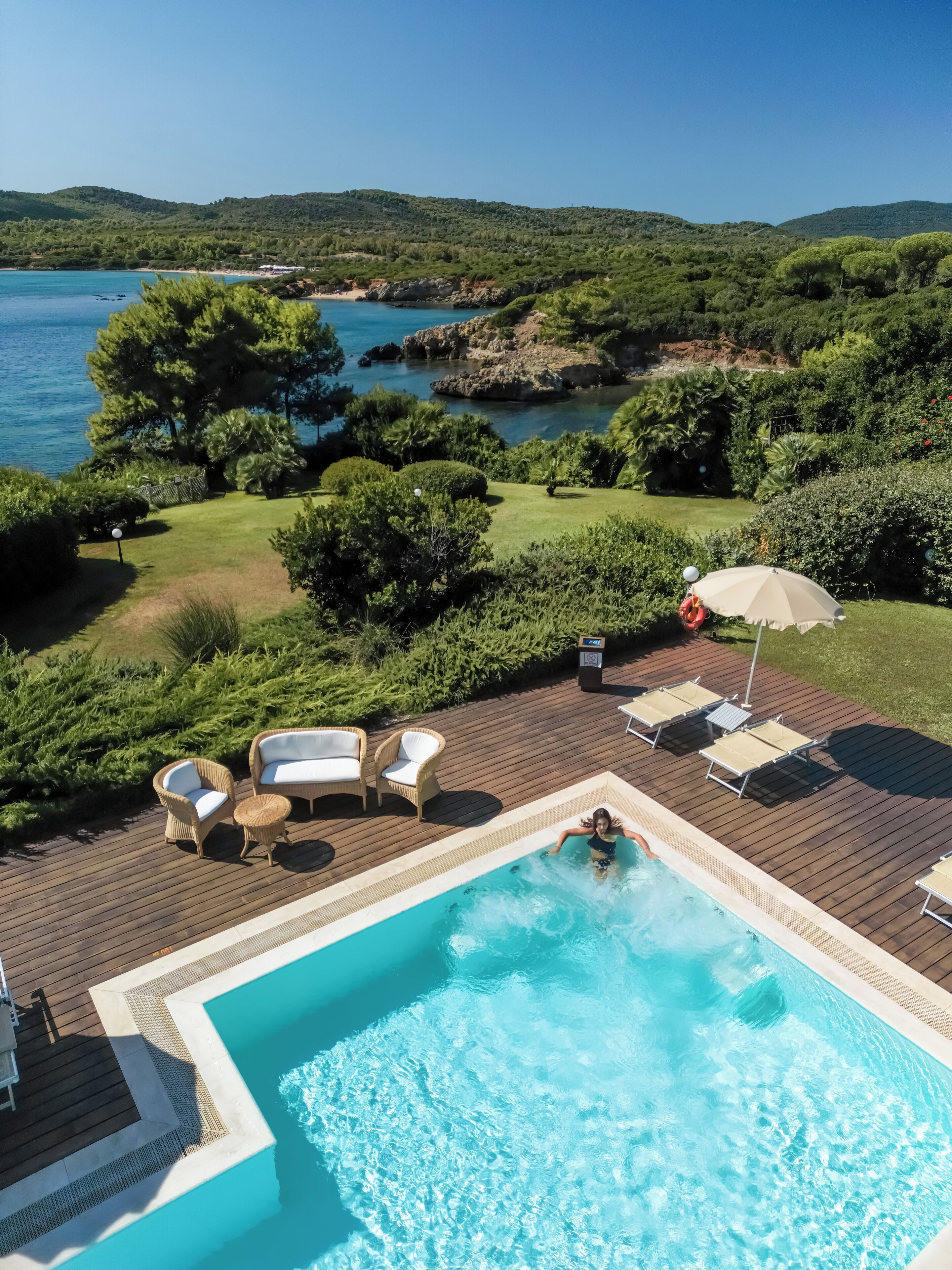 A swimming pool with lounge chairs and a view of the sea.