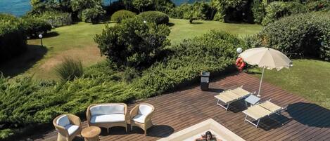 A swimming pool with lounge chairs and a view of the sea.